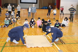 消防団が毛布だけで作る簡易担架を作っています(ホームページ委員会撮影) 消防団が毛布だけで作る簡易担架を作っています