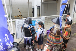 商工会館横の長曾我部香西攻絵図を見ています(ホームページ委員会撮影) 商工会館横の長曾我部香西攻絵図を見ています