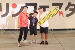 ラムネ早飲みで勝利し金メダルをかけてもらった参加者です(ホームページ委員会撮影) ラムネ早飲みで勝利し金メダルをかけてもらった参加者です
